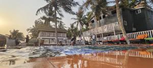 a swimming pool in front of a hotel with palm trees at SunRise Beach Resort in Iberekodo