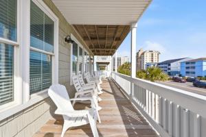a row of white chairs on the porch of a house at Anchor Down Luxury Ocean View Beach House w Pool in Myrtle Beach