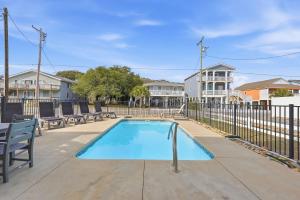 a swimming pool with benches and a fence at Anchor Down Luxury Ocean View Beach House w Pool in Myrtle Beach