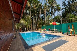 a swimming pool with a table and an umbrella at Cabanas Retreat in Revadanda