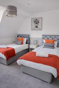 a bedroom with two beds with orange and gray at That's Amore House 3 bedroom house with parking walking distance to Sandbach town in Sandbach