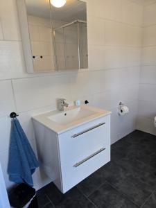 a white bathroom with a sink and a mirror at Sandra Fewo nähe Rømø in Bredebro in Bredebro +5 photos