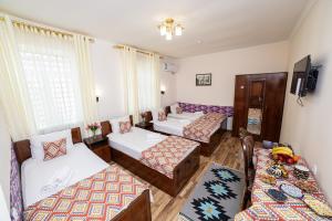 a room with four beds and a tv at Caravan Boutique Ichan Kala in Khiva