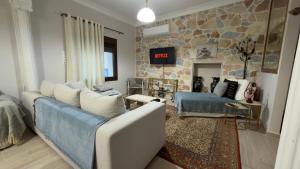 a living room with a blue couch and a stone wall at Hermione's house in Vrontádos
