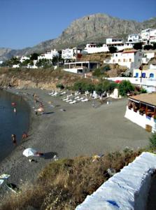 a beach with a group of people in the water at Louis Studios and Apartments Melitsaha Beach in Kalymnos