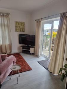 a living room with a tv and a sliding glass door at Halwyn View in St Austell