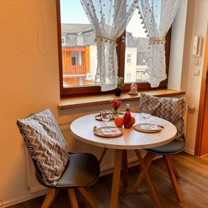 a dining room table with two chairs and a window at Ferienwohnung Meerane Zentrum in Meerane