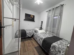 two beds in a small room with a window at El Capricho de Nunu SIMANCAS in Simancas