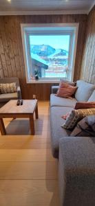 a living room with a couch and a table and a window at Sentral leilighet på Geilo in Geilo