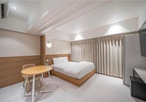 a bedroom with a bed and a table and a tv at 9AVENUE hotel in Daegu