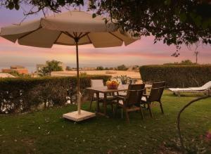 a table and chairs under an umbrella in the grass at Unique cozy villa sea view in Hurghada