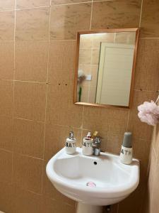 ein Badezimmer mit einem weißen Waschbecken und einem Spiegel in der Unterkunft Harmony House in Al Muwayqi‘ī