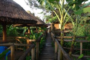 a wooden path leading to a restaurant with thatched umbrellas at Sunscape lodge in Fort Portal