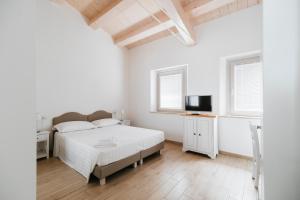 a white bedroom with a bed and a television at Il Conventino 46 in Falconara Marittima