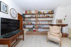 a living room with a tv and a desk and a clock at Ca du Aldo - La Crema in Finale Ligure