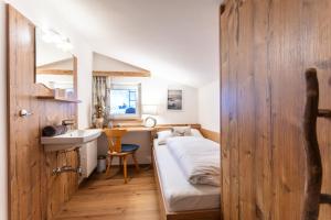 a small bedroom with a bed and a sink in it at Neuhof Appartements in Maishofen