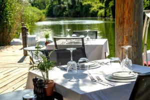 a table with plates and glasses on a table with a lake at Wineport Lodge Agva Riverside Hotel & Winery in Ağva