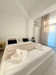a white bedroom with a large bed with towels on it at Amira Residence in Eforie Nord