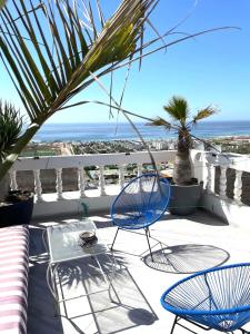 a patio with chairs and a table and a view of the ocean at Villa grand large in Tamraght Ouzdar