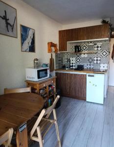 a kitchen with a wooden table and a microwave at Studio en station de ski familiale, vue sur les montagnes in La Morte
