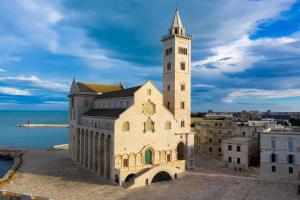 a building with a clock tower next to the water at Il Nido della Gioia Affittacamere in Trani +19 photos