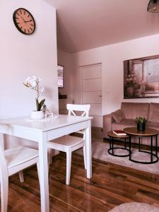 a white dining room table with chairs and a clock at Apartments Pablo Novalja in Novalja +6 photos