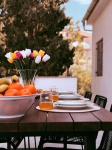 a table with a bowl of oranges and flowers on it at Apartments Pablo Novalja in Novalja