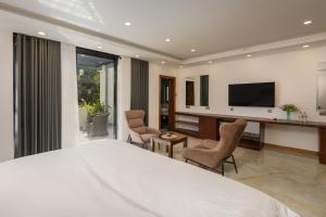 a bedroom with a large white bed and a television at Lasantha's Residence in Kadawata