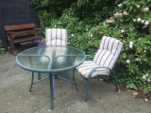 2 chaises et une table en verre ainsi qu'une table et des chaises dans l'établissement Davidsons Luxury Homestay, à Lower Hutt