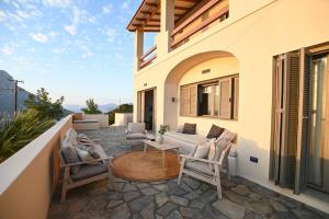 a patio with a couch and chairs on a balcony at Villa Pothaia in Myrties