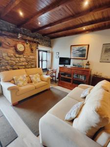 a living room with two couches and a tv at Cau La Mar in Lastres