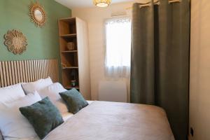a bedroom with a bed with two pillows and a window at Le reflet de Cabourg avec accès direct plage in Cabourg
