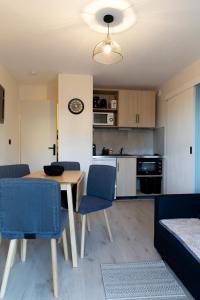 a living room with a table and chairs and a kitchen at Le reflet de Cabourg avec accès direct plage in Cabourg