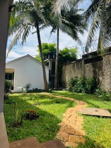 a house with palm trees and a brick walkway at La Petite Maison in Antsiranana