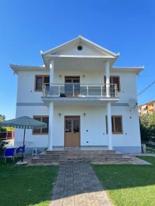 a white house with a balcony and an umbrella at VillaSolmare Velipoje in Velipojë