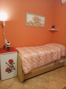 a small bed in a room with an orange wall at B&B JOY in Nettuno
