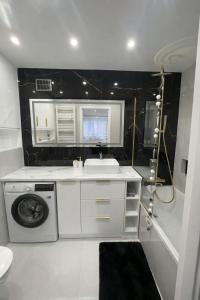 a bathroom with a sink and a washing machine at Mazurski Apartment in Ełk