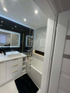a white bathroom with a sink and a shower at Mazurski Apartment in Ełk
