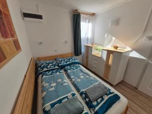 a bedroom with a bed with blue sheets and a window at Flóra apartmanház a Balatonnál in Lovas +145 photos