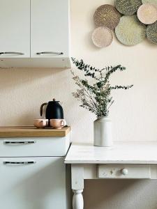 a white table with a vase with a plant on it at KÜCHWALDBLICK Designsuite in Chemnitz +9 photos