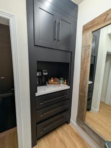 a kitchen with black cabinets and a mirror at Beamsville Modern Rustic Suites in Beamsville