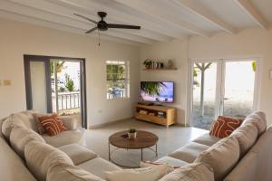 a living room with a couch and a tv at Nos Casita - 5 min walk to the beach in Pos Chiquito