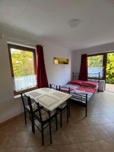 a room with two beds and a table and chairs at Flóra apartmanház a Balatonnál in Lovas