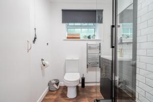 a white bathroom with a toilet and a window at New Forest Cottage with Hot Tub, Fireplace and Private Garden in Cadnam