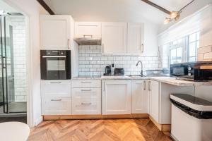 a kitchen with white cabinets and black appliances at New Forest Cottage with Hot Tub, Fireplace and Private Garden in Cadnam
