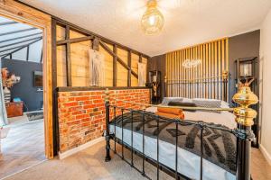 a bedroom with a bed and a brick wall at New Forest Cottage with Hot Tub, Fireplace and Private Garden in Cadnam