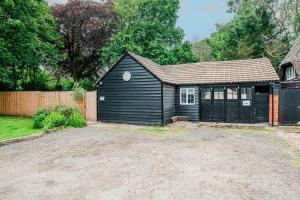 a small black house with a fence and a yard at New Forest Cottage with Hot Tub, Fireplace and Private Garden in Cadnam
