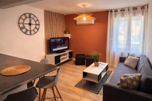 a living room with a couch and a tv at Duplex 2 chambres Meximieux centre ville in Meximieux