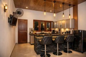 a kitchen with a bar with black stools at Ocean Green Villa in Matara