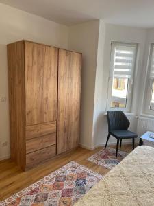 a bedroom with a large wooden cabinet and a chair at Ferienwohnung Blerta in Gerolstein